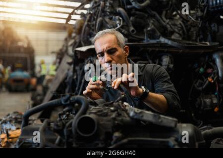 Homme attrayant travaillant dur et réparer mécanicien auto sur le moteur de voiture dans garage mécanique. Service de réparation Banque D'Images