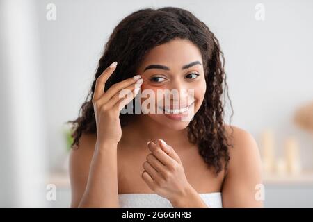 Jolie femme millénaire faire des procédures de beauté du visage dans la salle de bains à la maison ou spa, soins de la peau, cosmétologie Banque D'Images