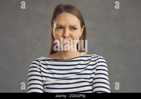 Portrait de la jeune femme qui fait des lèvres et qui regarde loin avec une drôle d'expression mécontent du visage Banque D'Images