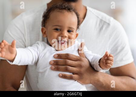 Gros plan Portrait d'adorable bébé noir reposant dans les mains du Père Banque D'Images