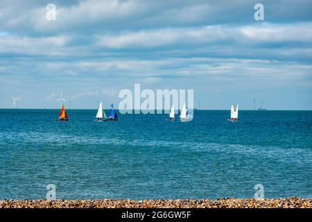 Des canots de voile qui se dispucent au large de la plage à Hampton, Herne Bay, Kent. Au loin se trouvent les éoliennes de la Thames wind Array, au Royaume-Uni Banque D'Images