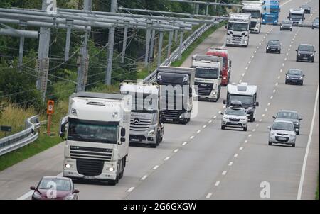 Reinfeld dans Holstein, Allemagne. 06e juillet 2021. Les camions empruntent la voie d'essai E-Highway sur Autobahn 1 entre Reinfeld et Lübeck. Dans le cadre de sa visite d'été, le ministre de l'Environnement du Schleswig-Holstein, Albrecht, a découvert la piste d'essai de l'autoroute E sur Autobahn 1 entre Reinfeld et Lübeck. Sur la piste d'essai de cinq kilomètres de long de l'autoroute E, un camion hybride du transitaire effectue plusieurs navettes par jour entre Reinfeld et le port de Lübeck. Une ligne aérienne alimente le véhicule en électricité. Credit: Marcus Brandt/dpa/Alay Live News Banque D'Images