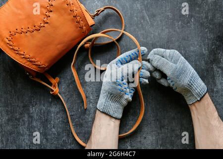 Professionnel du cuir fait un trou dans l'épaule sangle en cuir d'un sac à main de womans, vue de dessus, occupations Banque D'Images