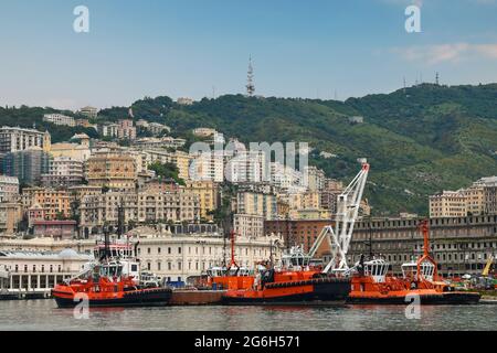 Vue panoramique sur le Vieux Port (Porto Antico) avec des remorqueurs amarrés et la ville sur la colline en arrière-plan, Gênes, Ligurie, Italie Banque D'Images