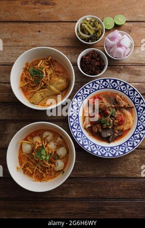 Cuisine locale du nord de la Thaïlande nouilles aux œufs curry avec poulet et boulettes de viande et nouilles de riz sur fond de bois Banque D'Images