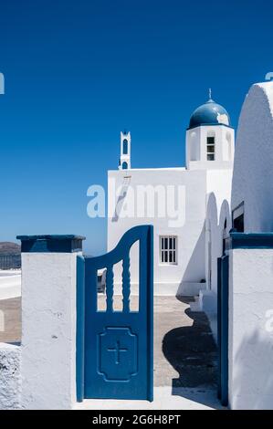 Petite porte en bois de l'église orthodoxe grecque traditionnelle sur l'île de Santorini. Porte bleue ouverte. Jour ensoleillé. Ciel bleu. Personne. Banque D'Images