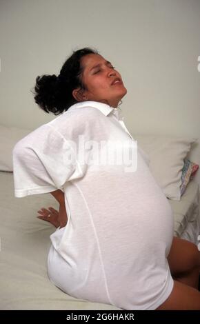 femme hispanique très enceinte dans le travail souffrant de mal de dos Banque D'Images