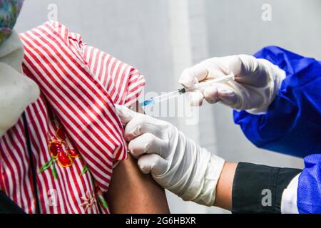 Bandung, Indonésie. 06e juillet 2021. Une femme reçoit une dose du vaccin Covid-19 au marché moderne Sarijadi à Bandung. Le ministre de la Santé, Budi Gunadi Sadikin, a déclaré que le ministère de la Santé (Kemenkes) continuera de faire augmenter le taux de vaccination contre le coronavirus (Covid-19) à 5 millions de doses par jour. Crédit : SOPA Images Limited/Alamy Live News Banque D'Images