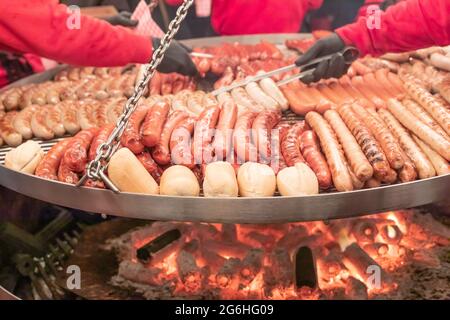 diverses saucisses sont préparées sur un grand gril pivotant Banque D'Images