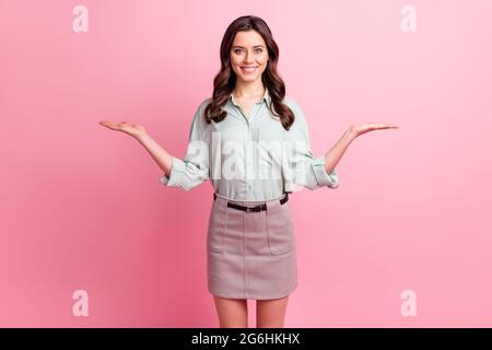 Photo de jolie petite femme douce porter une chemise verte tenant les bras vide espace montrant des échelles souriant isolé couleur rose fond Banque D'Images