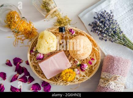 Different natural dried herbs flower petals used in beauty bath products concept. Top view of bath bomb, natural sea sponge, bar of soap, aroma oil bo Banque D'Images