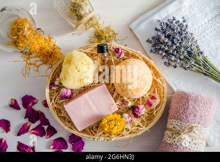 Différents pétales de fleurs d'herbes séchées naturelles utilisés dans les produits de bain de beauté concept. Vue de dessus de la bombe de bain, éponge de mer naturelle, barre de savon, huile aromatique bo Banque D'Images