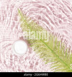 Blanc visage crème et vert fougères feuille dans l'eau avec de petites vagues sur fond rose pastel doux avec tuiles. Produits de beauté de luxe pour femmes. Style minimaliste Banque D'Images