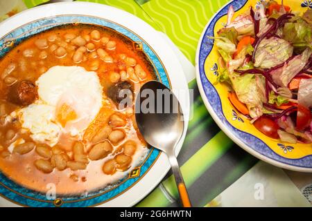 Vue sur les assiettes avec la typique Fabada asturiana espagnole et salade mixte Banque D'Images