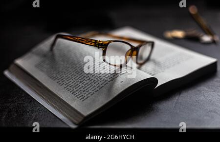 Une paire de lunettes de lecture reposant sur un livre ouvert.