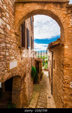 Spello, charmante voie du centre historique avec arche en pierre et vue sur la campagne de l'Ombrie Banque D'Images