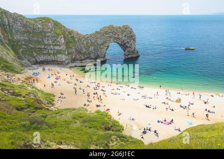 Touristes à la plage à l'emblématique arche de mer Durdle Door lors d'une journée ensoleillée d'été sur la côte jurassique à Dorset, Royaume-Uni. Banque D'Images