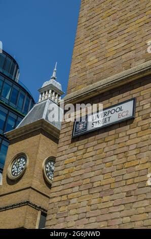Un panneau de rue à l'extérieur de la gare de Londres Liverpool Street avec une tour de l'horloge en arrière-plan. Il y a un ciel bleu par une chaude journée d'été dans la ville. Banque D'Images