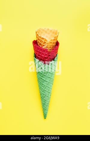 Divers cônes de glace vides sur fond jaune vif. Concept d'été, vue du dessus. Banque D'Images