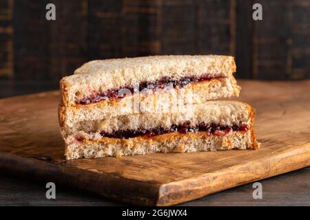 Un sandwich au beurre d'arachide et à la gelée de raisin sur une planche à découper en bois Banque D'Images
