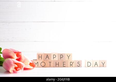 Fête des mères contexte avec écriture sur des lettres bloc avec des tulipes roses Banque D'Images