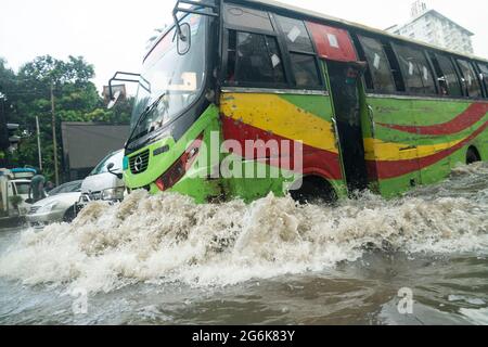 Un bus traversant de l'eau de pluie sur une route inondée pendant la pluie de mousson. Quelques heures de pluie créent de l'engorgement dans les rues car le système d'égouts et de drains n'est pas nettoyé et entretenu correctement. Dhaka, Bangladesh. Banque D'Images