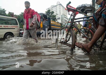 Un homme livrant de la nourriture marche à travers l'eau de pluie avec une parcelle pendant une grosse versante. Quelques heures de pluie créent de l'engorgement dans les rues car le système d'égouts et de drains n'est pas nettoyé et entretenu correctement. Dhaka, Bangladesh. Banque D'Images