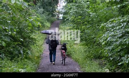 Stuttgart, Allemagne. 07e juillet 2021. Un homme marche dans les bois avec un parapluie dans une pluie persistante. Credit: Bernd Weißbrod/dpa/Alay Live News Banque D'Images