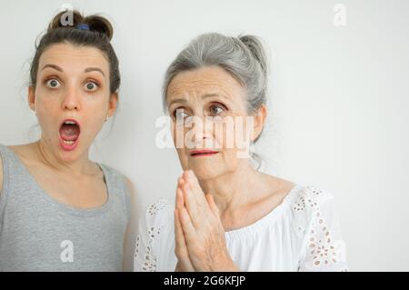 Une fille adulte émotive avec sa mère senior crient et regardent la caméra, une famille folle de différentes générations d'âge s'amusant sur blanc Banque D'Images