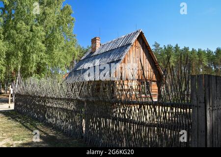 Ancienne ferme en bois entourée d'une clôture en osier. Ancienne ferme traditionnelle placée dans un musée en plein air à Wdzydze Kiszewskie Banque D'Images