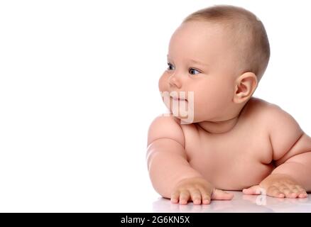 Enfant bébé enfant bébé fille enfant dans la couche est couché sur son ventre et regarde de côté attentivement Banque D'Images