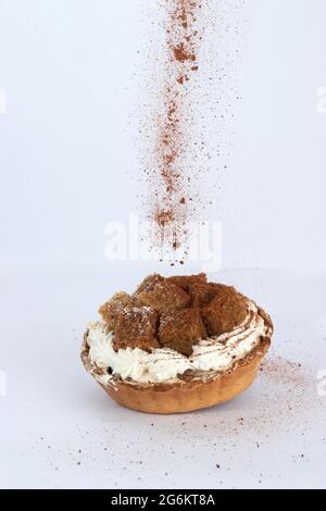 Poudre de café arrosée sur un Banoffee Pie sur fond blanc Banque D'Images