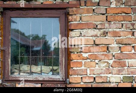 Vieux mur de briques avec une fenêtre en bois. Avec grilles métalliques. Affichage d'une ancienne maison dans la fenêtre Banque D'Images