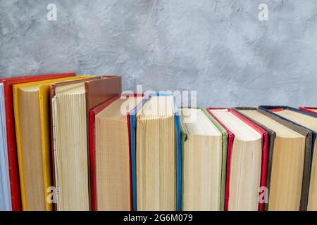 Rangée de livres en bois dur multicolores sur table en bois contre un mur en béton gris et bleu Banque D'Images