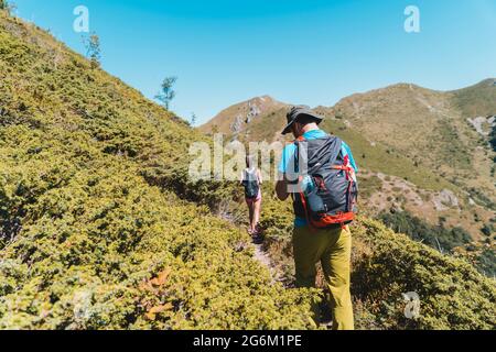 Randonneurs marchant sur le sentier de montagne dans les buissons Banque D'Images