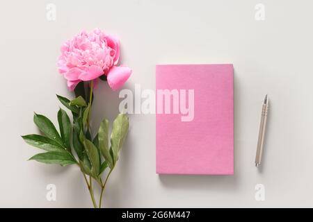 Maquette féminine créative avec tasse à café, cahier de fleurs de pivoine rose. Copier l'espace. Vue du dessus, plan d'appartement. Banque D'Images