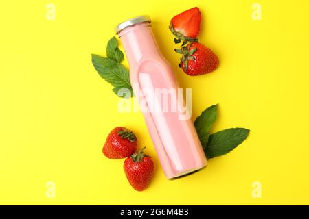 Bouteille de milkshake aux fraises et ingrédients sur fond jaune Banque D'Images