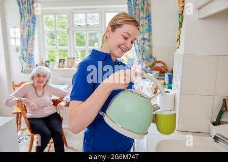 Femme Accueil aider à faire une tasse de thé dans la cuisine tout en discutant avec la femme sénior Banque D'Images