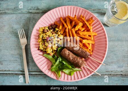 Repas végétalien sur assiette avec Kofta Kebabs à base de plantes avec frites de pommes de terre douces et couscous et salade Banque D'Images