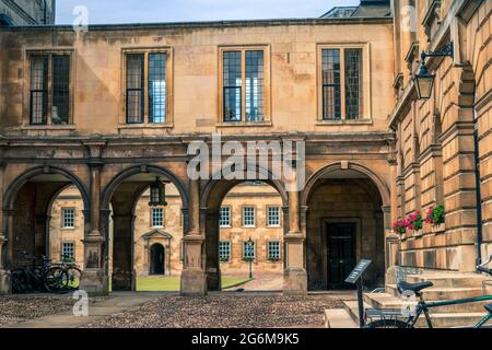 Première cour de Peterhouse College Université de Cambridge avec passerelle voûtée avec galeries au-dessus et cycles en premier plan sur terrain pavé Banque D'Images