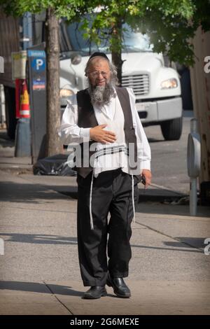 Un juif ultra-orthodoxe portant le tzitzit, marche sur Lee Avenue à Williamsburg, Brooklyn, New York. Banque D'Images