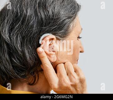 Prothèse auditive derrière l'oreille d'une femme âgée, gros plan Banque D'Images