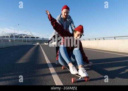 Homme et femme élégants patinant à bord de la longboard Profitez de leur temps ensemble. Mode urbain et activité tendance Banque D'Images