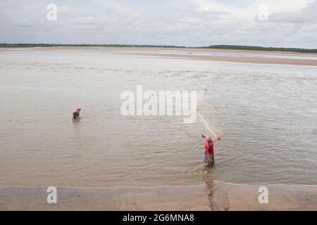 Pêcheur jetant le filet de pêche au confluent de la rivière pour la pêche. Banque D'Images