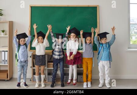 Drôle de petits diplômés de maternelle ou secondaire qui sont vêtus de planches de mortier. Banque D'Images