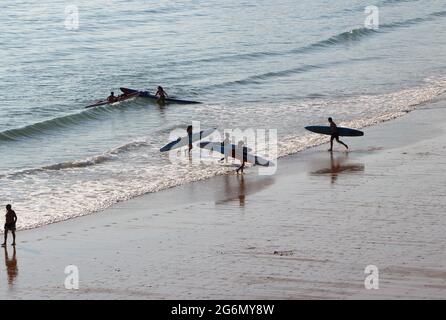 Jeunes avec planches de surf et skis de surf entrant dans l'océan lors d'un matin ensoleillé de printemps Sardinero Santander Cantabria Espagne Banque D'Images