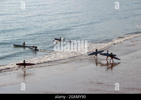 Jeunes avec planches de surf et skis de surf entrant dans l'océan lors d'un matin ensoleillé de printemps Sardinero Santander Cantabria Espagne Banque D'Images