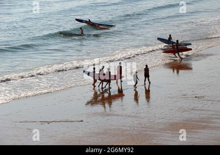 Jeunes avec planches de surf et skis de surf entrant dans l'océan lors d'un matin ensoleillé de printemps Sardinero Santander Cantabria Espagne Banque D'Images