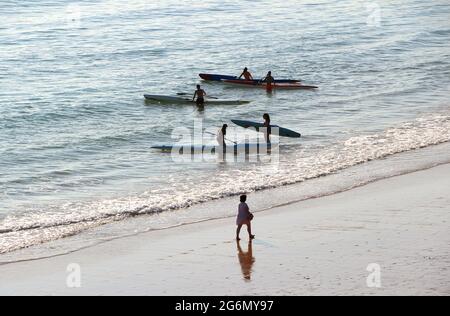 Jeunes avec planches de surf et skis de surf entrant dans l'océan lors d'un matin ensoleillé de printemps Sardinero Santander Cantabria Espagne Banque D'Images