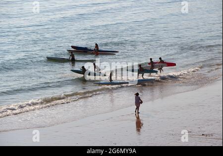 Jeunes avec planches de surf et skis de surf entrant dans l'océan lors d'un matin ensoleillé de printemps Sardinero Santander Cantabria Espagne Banque D'Images